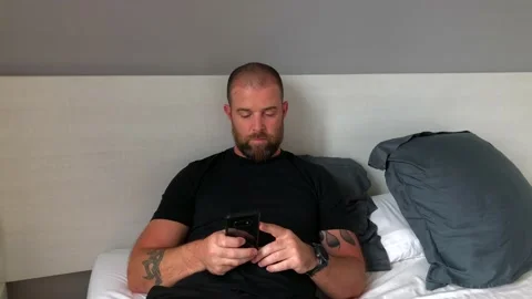 Bearded mid aged man using phone in bed Stock Footage 152424339
