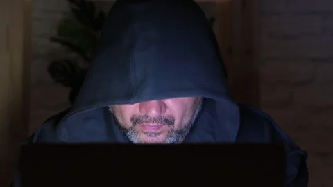 Bearded middle aged hooded hacker typing on laptop at night Stock Footage 274343725