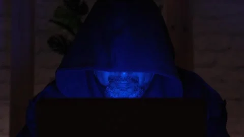 Bearded middle aged hooded hacker using laptop under the blue neon light sparkle Stock-Footage 274697227
