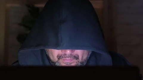 Bearded middle aged hooded man typing on laptop at night close up Video stock 309558804