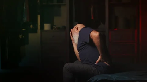 Bearded middle-aged man feels lower back pain at home, spine disorder Stock Footage 346714359