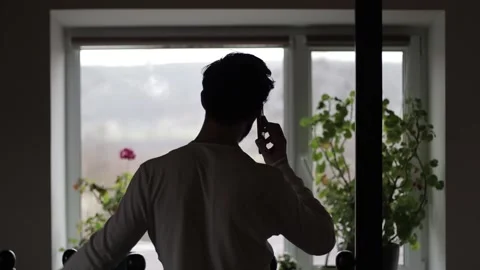 Bearded Middle Aged Man Talking on a Phone Indoors While Looking at a Window Video stock 237874546