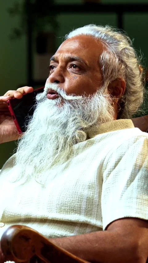 Bearded modern Indian man talking on mobile phone, resting on relaxing chair Video stock 342757030