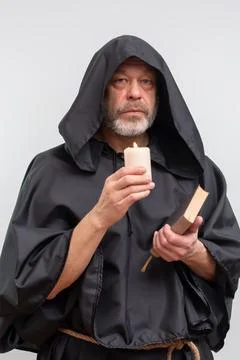Bearded monk in hood looking at camera by candle light. Photos