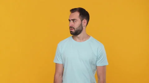 Bearded mysterious young man 20s in basic casual blue t-shirt isolated on yellow Stock Footage 148288317