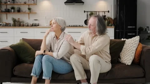 The bearded old man comforts his sad wife. The blond old woman is loved by her Stock Footage 262239877