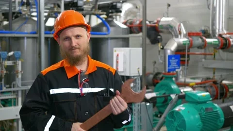 A bearded operator in an orange helmet holds a large wrench in his hands in the Stock Footage 169604388
