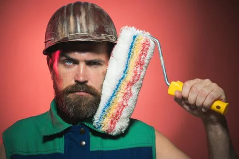 Bearded painter man in hard hat with paint roller. Male Construction worker.  Stock Photos