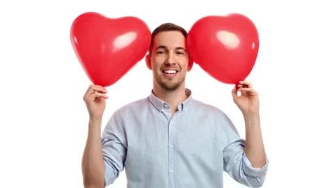 Bearded playful male posing with two red heart shape air balloon Saint Valentine Stock Footage 233790342