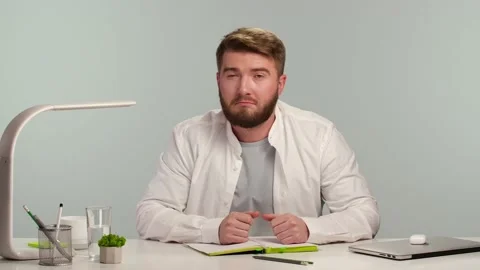Bearded positive man looks at camera, listens carefully information, shows Stock Footage 148092019