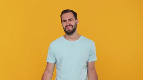 Bearded sad upset young man 20s in basic casual blue t-shirt isolated on yellow Video stock 148288446