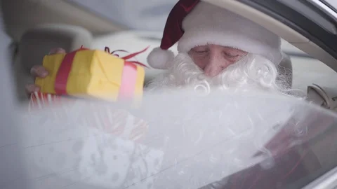 Bearded Santa giving present boxes to unrecognizable child from the car window Stock Footage 120909738