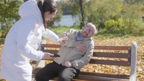 Bearded senior suffers heart attack on bench, passerby seeks help Stock Footage 297254964