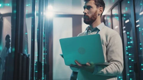 Bearded server specialist working in data center inspecting rack server cabinets Stock Footage 119232369