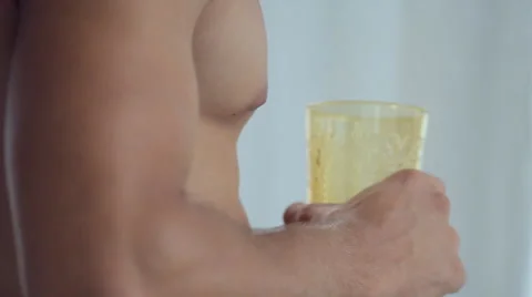 The bearded shirtless man standing at the window and drinking iced drink from a Stock Footage 51916380