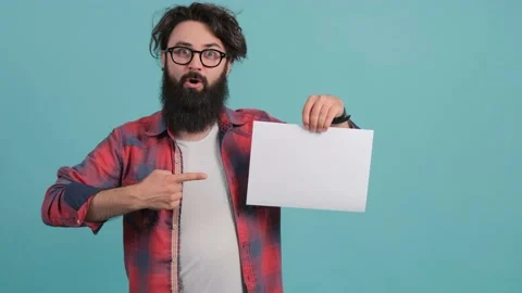 A bearded shocked young man points to a white sheet he holds in his hand. Stock Footage 142072862