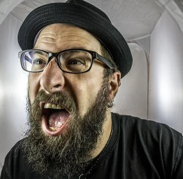 A bearded, shouting and angry looking man with black glasses Stock-Fotos