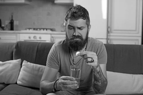 Bearded sick man throws a pill of flu in a glass water. Stock-Fotos