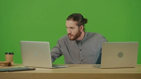 Bearded Student Freelancer Attentively Typing on 2 Laptops Working in Internet Stock Footage 220468171