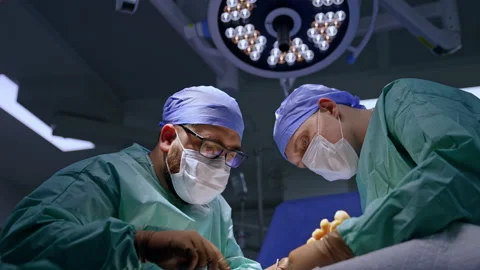 Bearded surgeon uses forceps carefully performing operation on foot Stock Footage 241285723