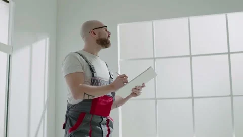 Bearded taskmaster writes ideas on clipboard in apartment Stock Footage 150100422