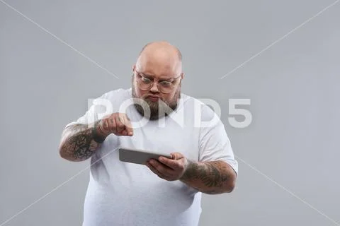 Bearded tattooed man with pouting lips playing in smartphone Stock Photos