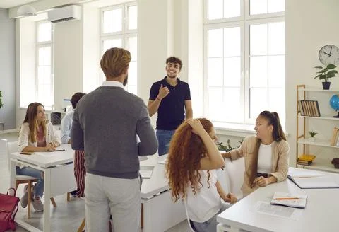 Bearded teacher communicates with student through desk against background of Stock Photos