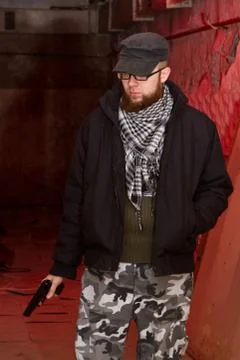 Bearded terrorist with a gun in the stroma of a dilapidated shelter Stock Photos