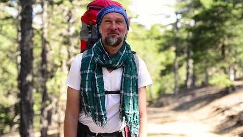 Bearded traveler, with backpack, is standing on a forest trail Video stock 83501925