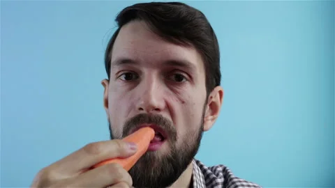 Bearded vegetarian vegan man eats fresh carrot Stock Footage 121326704