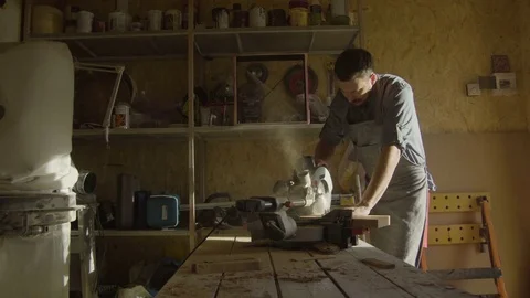 Bearded woodworker in apron work with woodworking machine at workshop with Stock-Footage 76088447