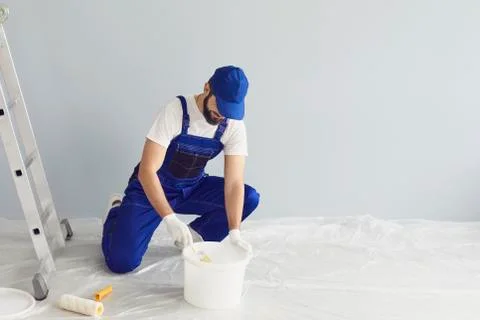 Bearded worker painter taking paint from bucket Stock Photos