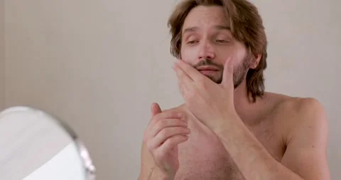 Bearded young with bare torso using moisturising mask for face. Bearded guy Stock Footage 142528851