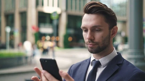 Bearded young businessman using his phone in city street and smiling Stock Footage 95591422
