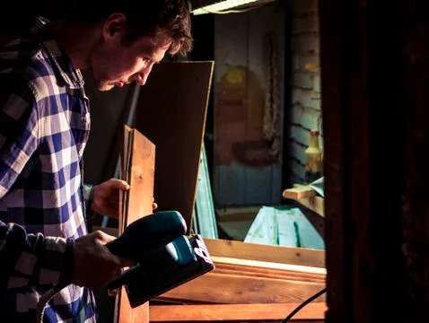 Bearded young carpeter working in the workshop with wooden material Stock Photos