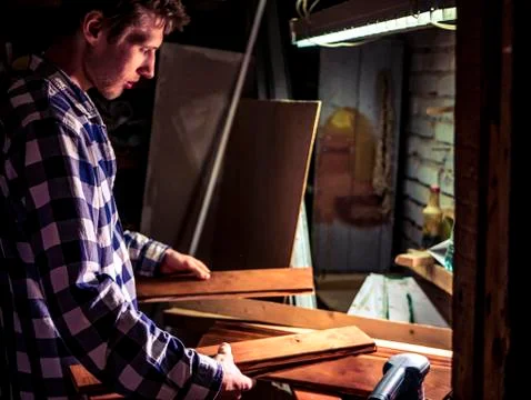 Bearded young carpeter working in the workshop with wooden material Stock Photos