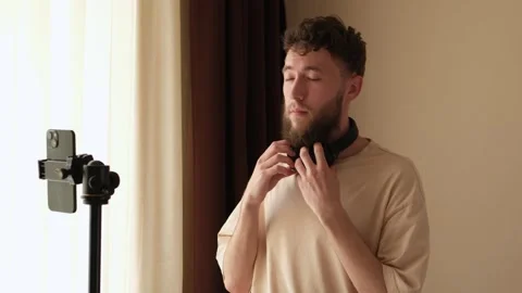 A bearded young guy sets up a phone stand to start online communication. Stock Footage 278798294