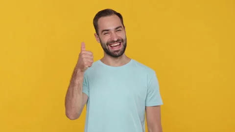 Bearded young man 20s in basic casual blue t-shirt on yellow background studio. Stock Footage 148282788