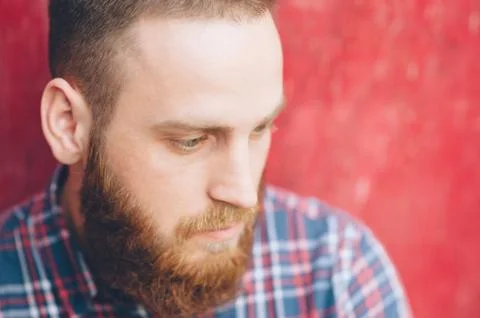 Bearded young man on a background of red wall 스톡 사진