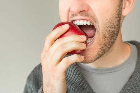 Bearded young man biting an apple Stock Photos