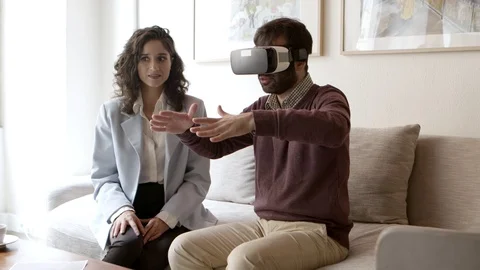 Bearded young man gesturing while using VR headset at home Stock Footage 121003338