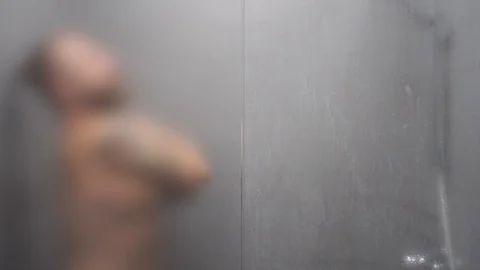 Bearded young man in shower. Blurry background - glass door is damp Stock Footage 110905729