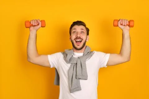 A bearded young mandoing exercises with two dumbbells Stock Photos