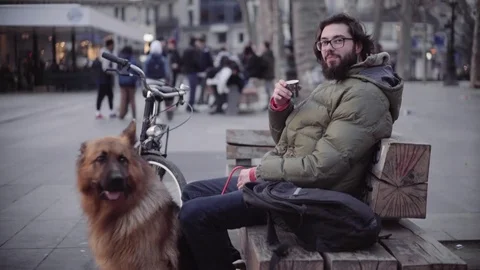 Beardy hipster looking into the camera and smiling, dog sitting next to him Stock Footage 70403920