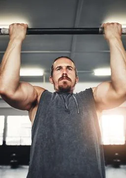 Beast mode activated. a young man doing pull ups in a gym. Stock Photos