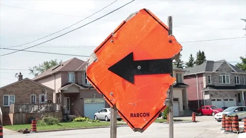 Beat up broken damaged orange diamond construction sign with black arrow Stock Footage 247753582