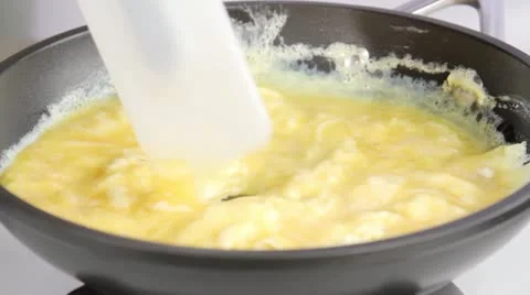 Beaten eggs being scrambled in a pan Video stock 24657284