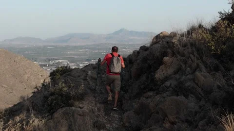Off the beaten path, a man in a red shirt and shorts climbs steep rocks wit.. Stock Footage 286813842