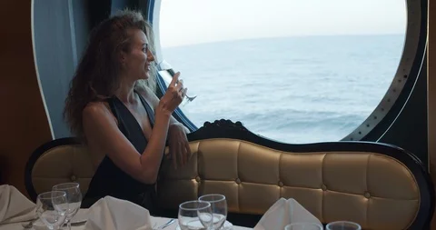 Beatiful woman is sitting alone at table in restaurant on cruise ship, drinking Stock Footage 120329672