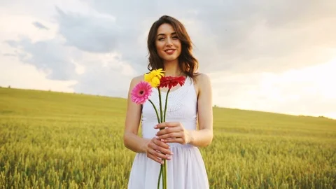 Beatiful young brunette woman stending in the golden field with beatiful bouquet Stock Footage